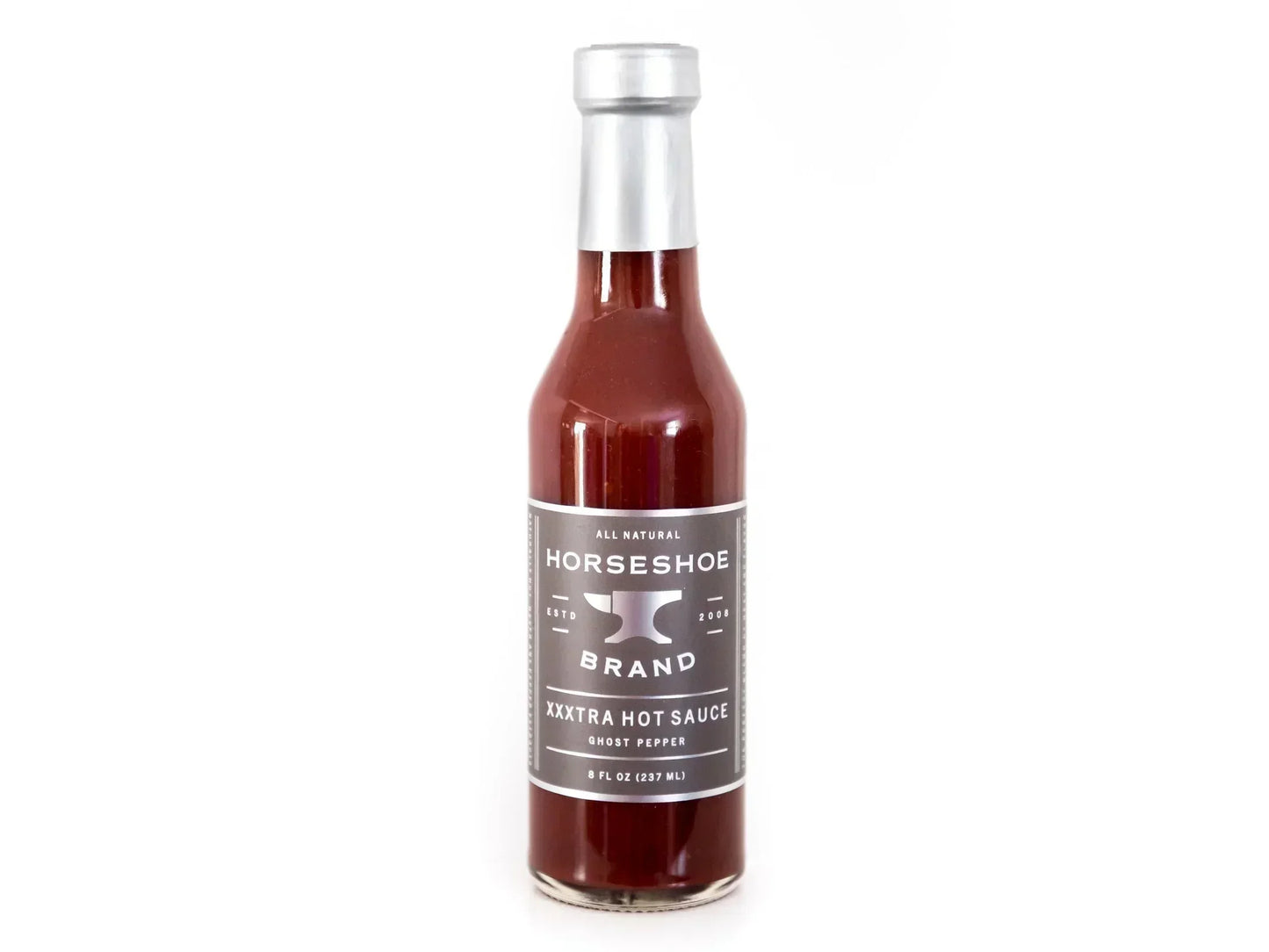 Ghost pepper hot sauce in clear glass bottle with silver label and cap on white background