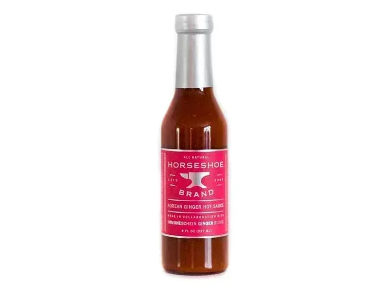 Glass bottle of Horseshoe Brand Korean ginger hot sauce with pink label on white background