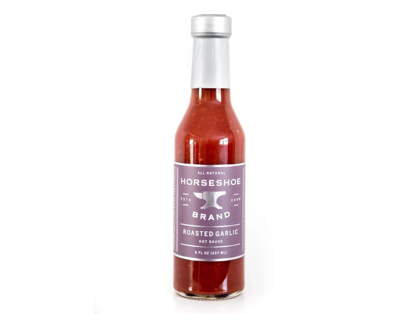 Roasted garlic hot sauce in glass bottle with silver cap, isolated on white background