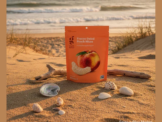 Freeze-dried peach slices pouch on sandy beach with shells and driftwood, ocean in background