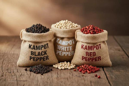 Burlap sacks of Kampot black, white, and red peppercorns on rustic wooden table