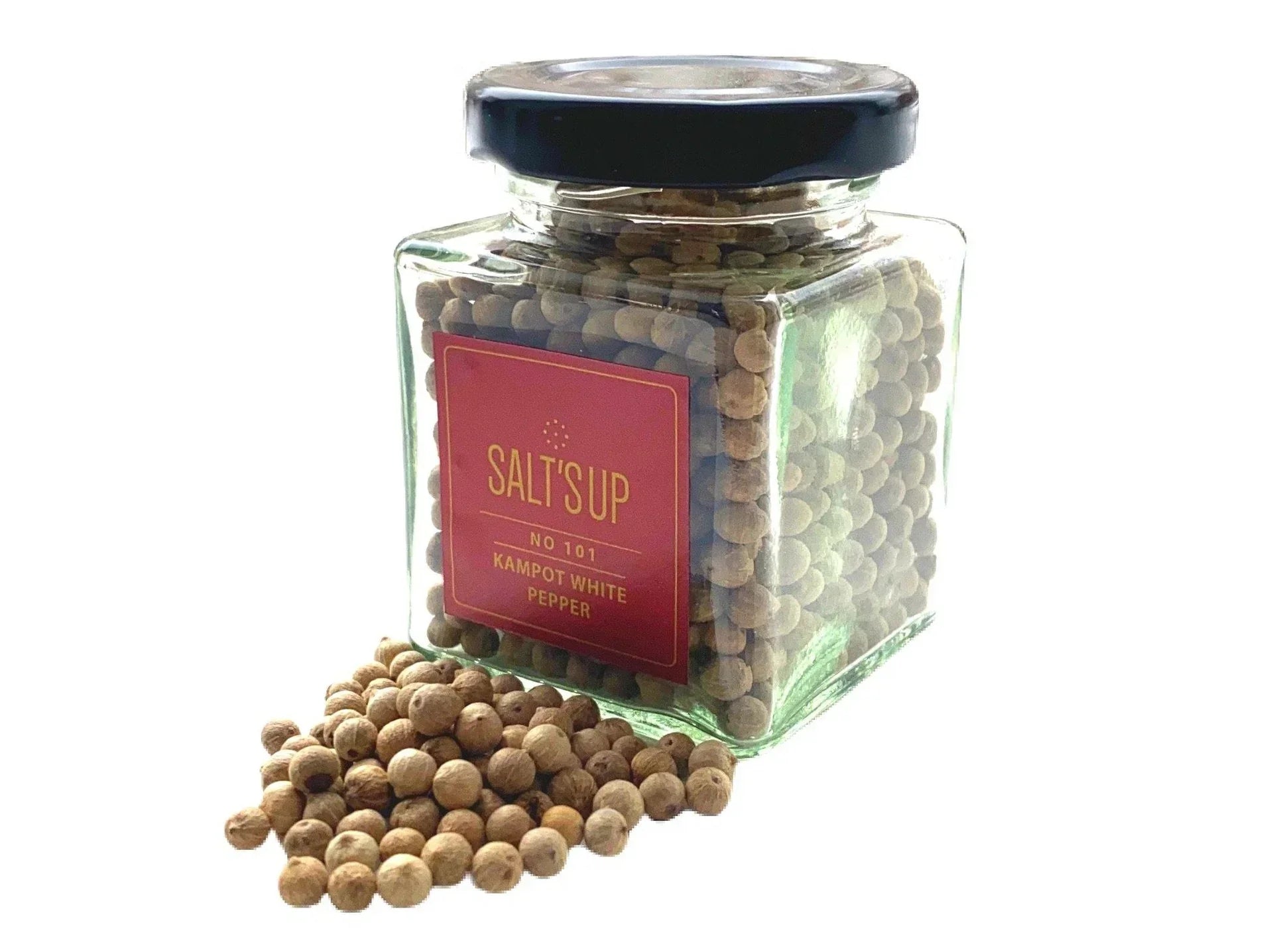 Glass jar of Kampot white peppercorns with some peppercorns spilled in front
