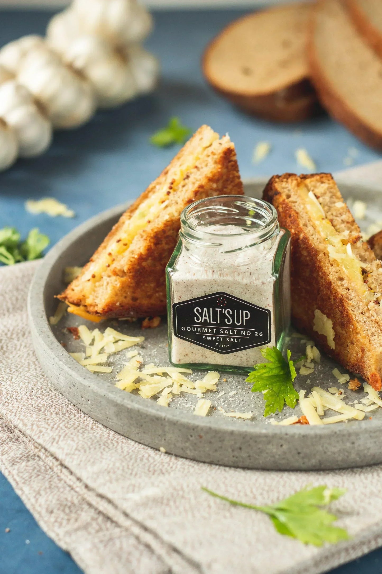 Grilled cheese sandwich with shredded cheese and Salt's Up gourmet salt jar on ceramic plate