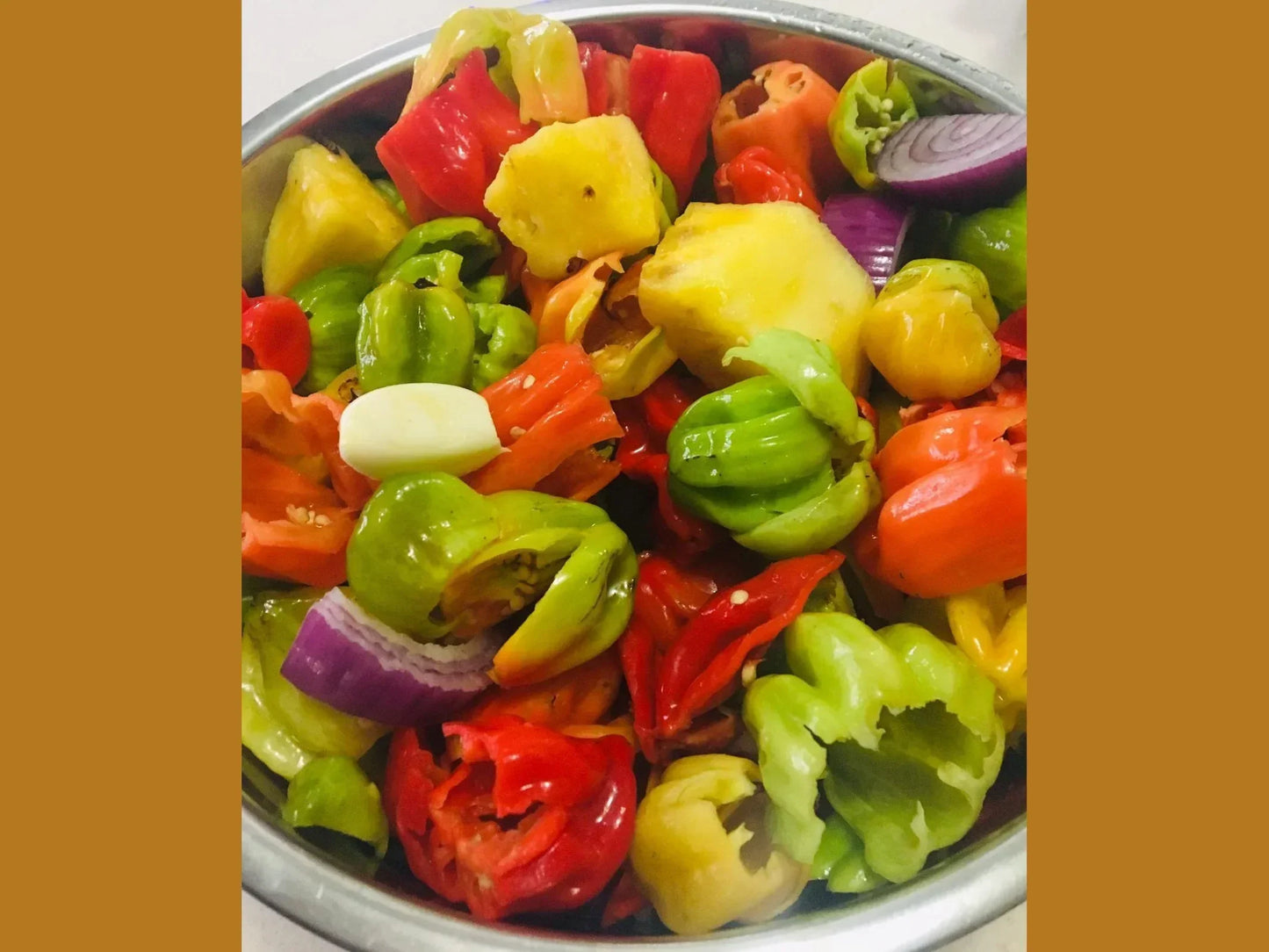 Bowl of colorful chopped hot peppers, garlic, onion, and pineapple for artisan hot sauce