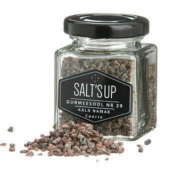 Glass jar of Salt's Up Gurmeesool Kala Namak coarse salt with spilled crystals, gourmet seasoning