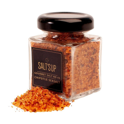 Glass jar of SALT'S UP chipotle sea salt with coarse red-orange salt grains spilled in front