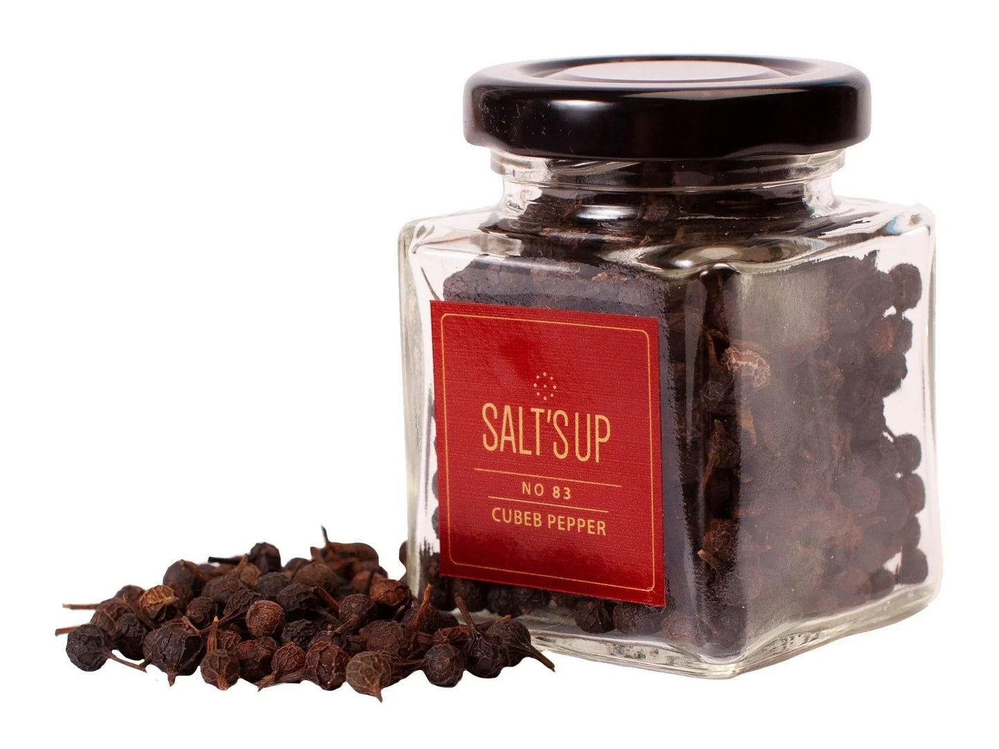 Glass jar of whole cubeb peppercorns with black lid and red label, peppercorns spilled beside.