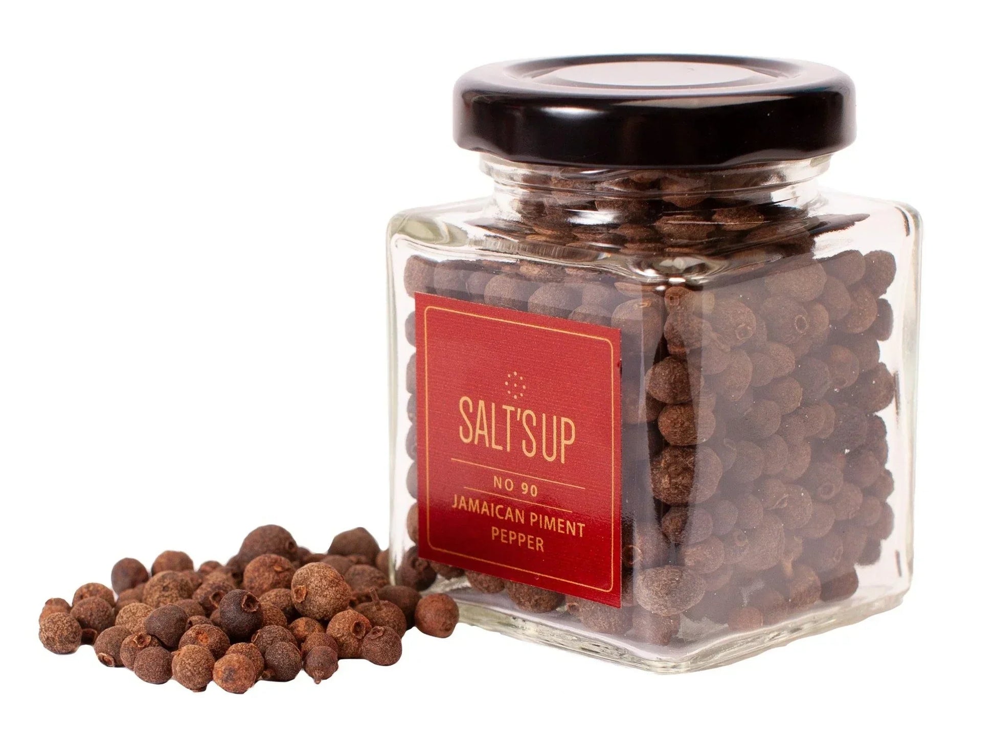 Glass jar of whole Jamaican piment pepper with loose peppercorns on white background