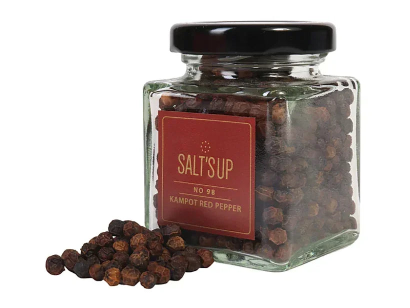 Glass jar of whole Kampot red peppercorns with label, some peppercorns spilled in front