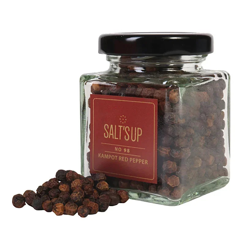 Glass jar of Kampot red peppercorns with Salt's Up label, loose peppercorns in front