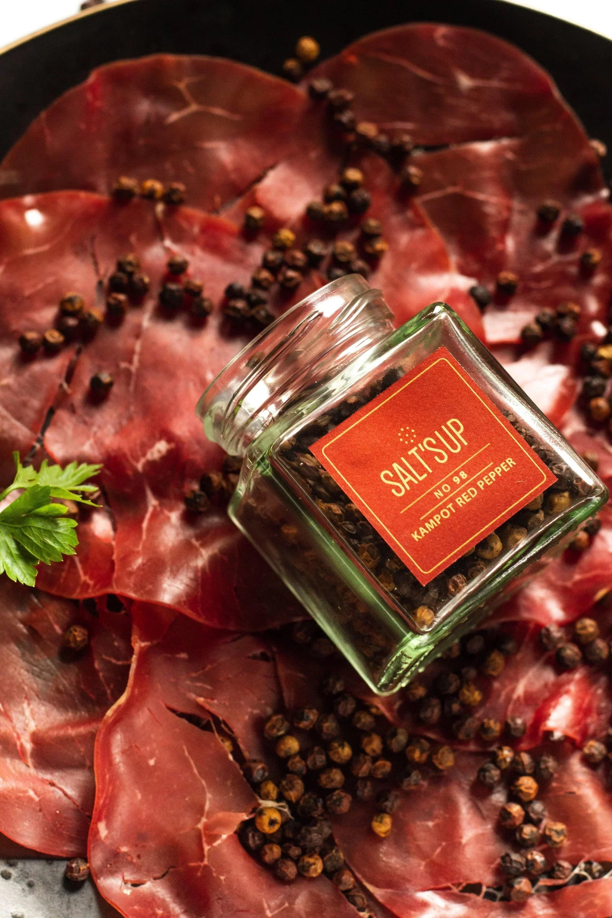 Jar of Kampot red pepper on cured meat slices, Spice n Slice Market gourmet product