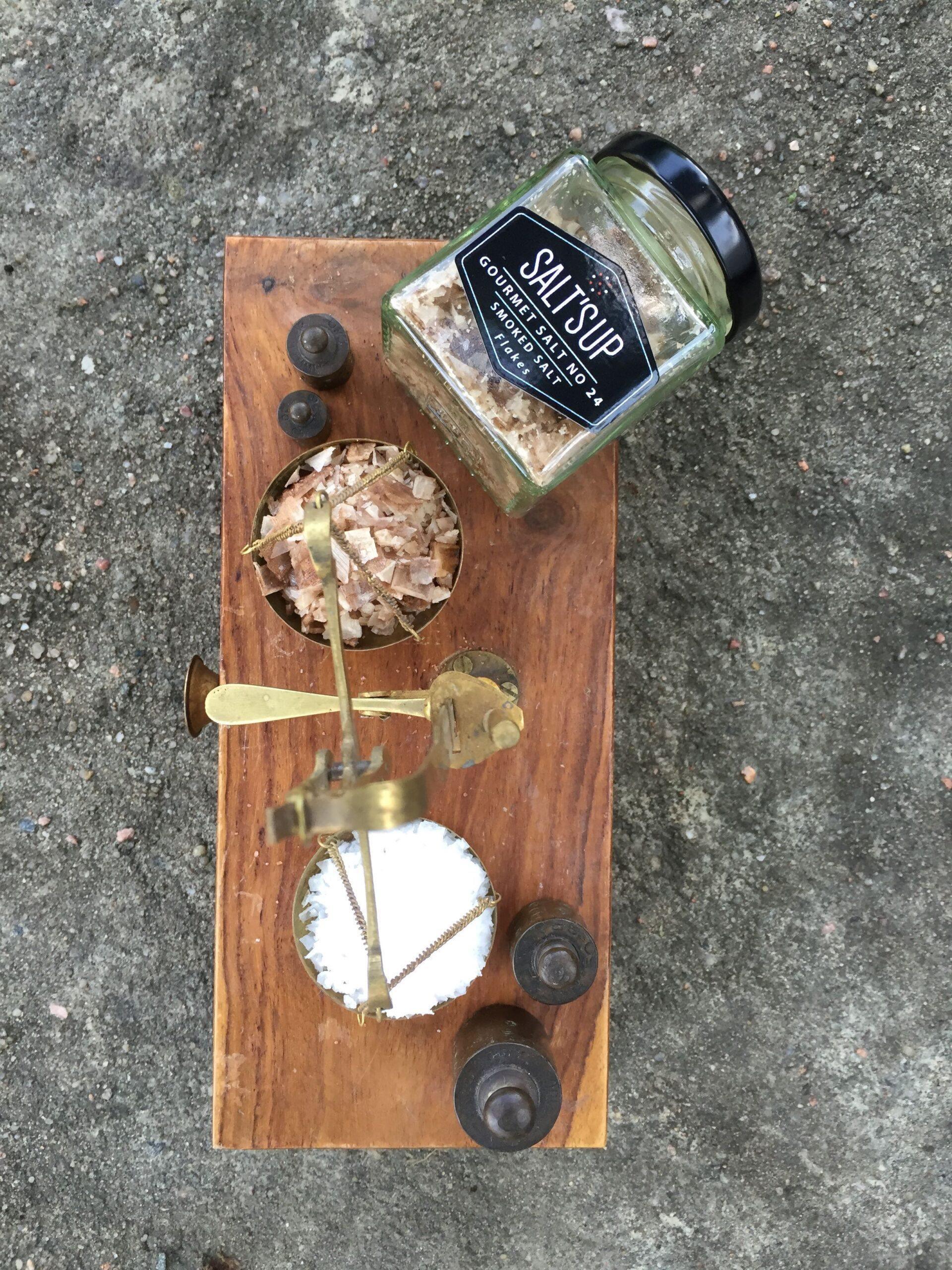 Glass jar of gourmet smoked salt with antique brass scale and salt on wooden base