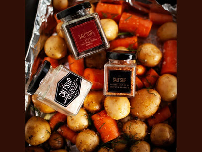 Gourmet spice jars on roasted potatoes and carrots in a foil baking tray