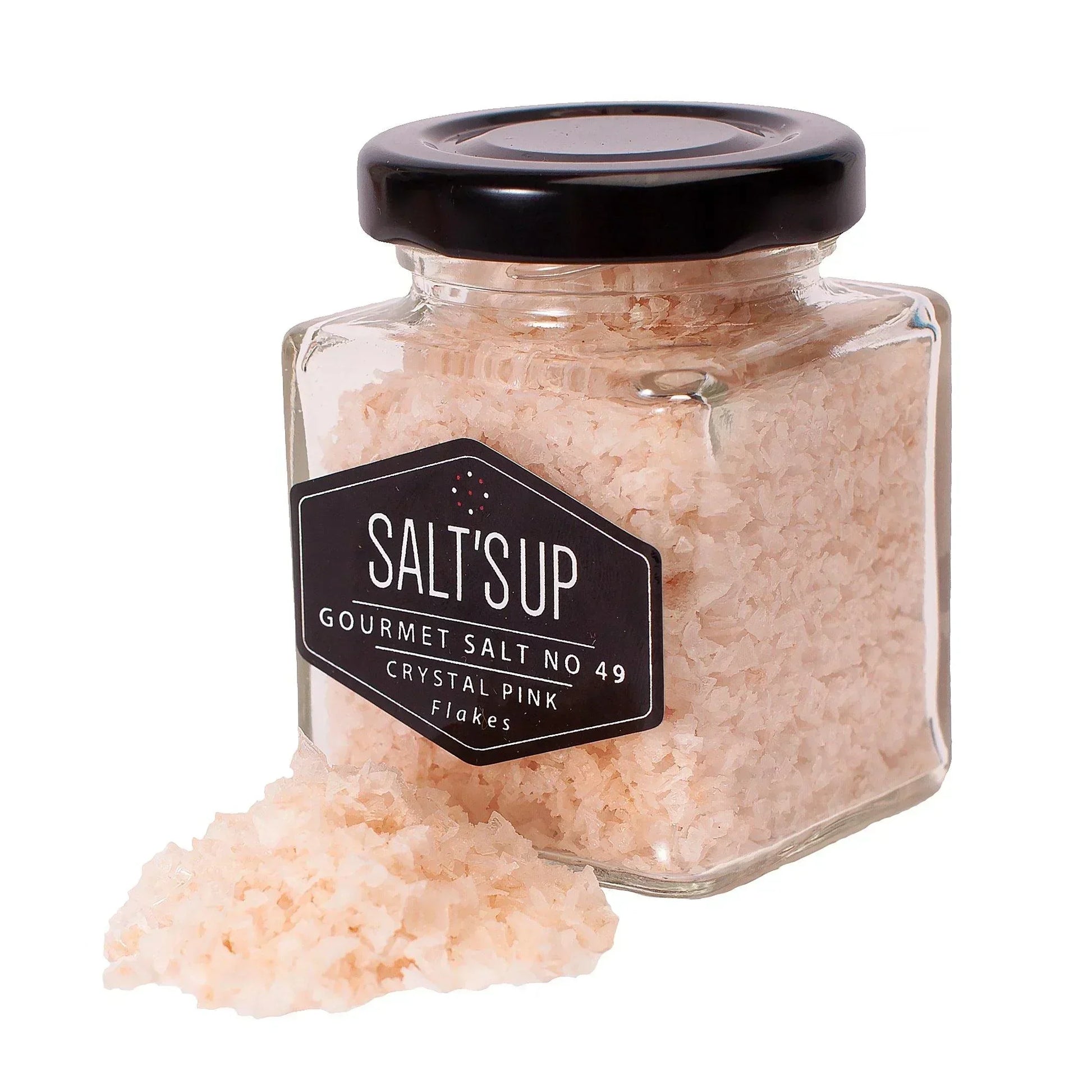 Glass jar of crystal pink gourmet salt flakes with salt spilled in front