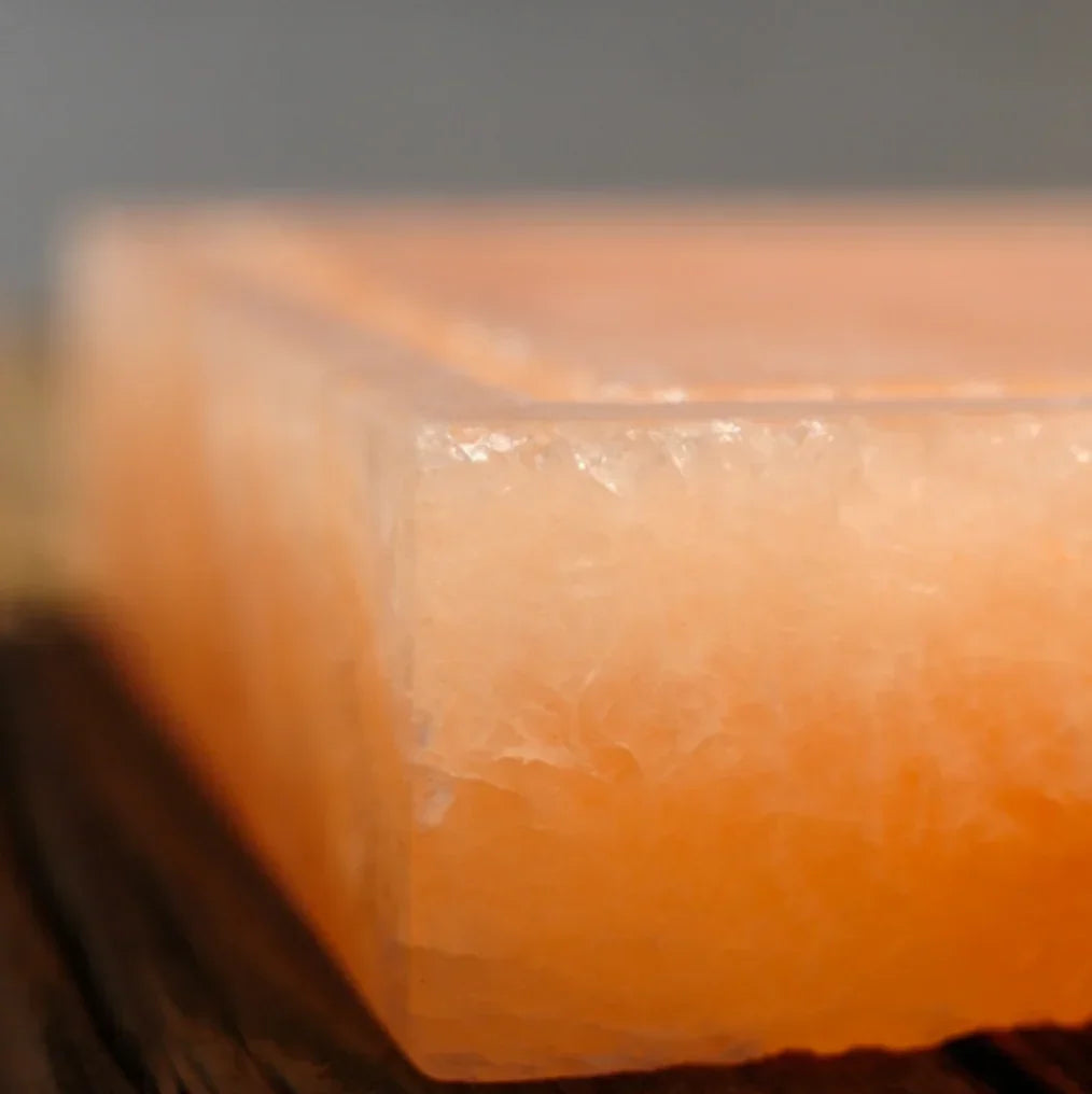 Close-up of a pink Himalayan salt block on a wooden surface, Spice n Slice Market gourmet kitchen accessory.