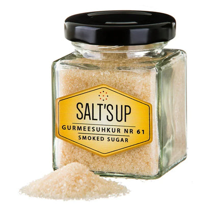 Glass jar of smoked sugar with black lid and loose gourmet sugar crystals in front