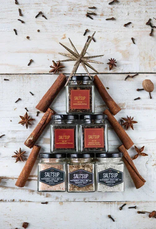 Gourmet salt and spice jars arranged in a tree shape with cinnamon sticks, cloves, and star anise