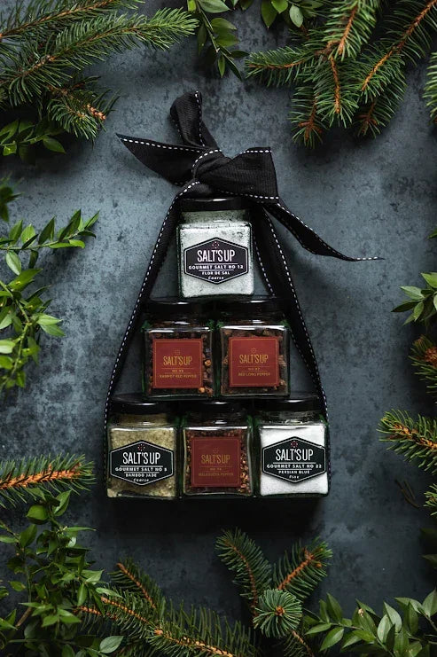Holiday gift set of artisan gourmet salt jars, arranged as a tree, surrounded by festive greenery