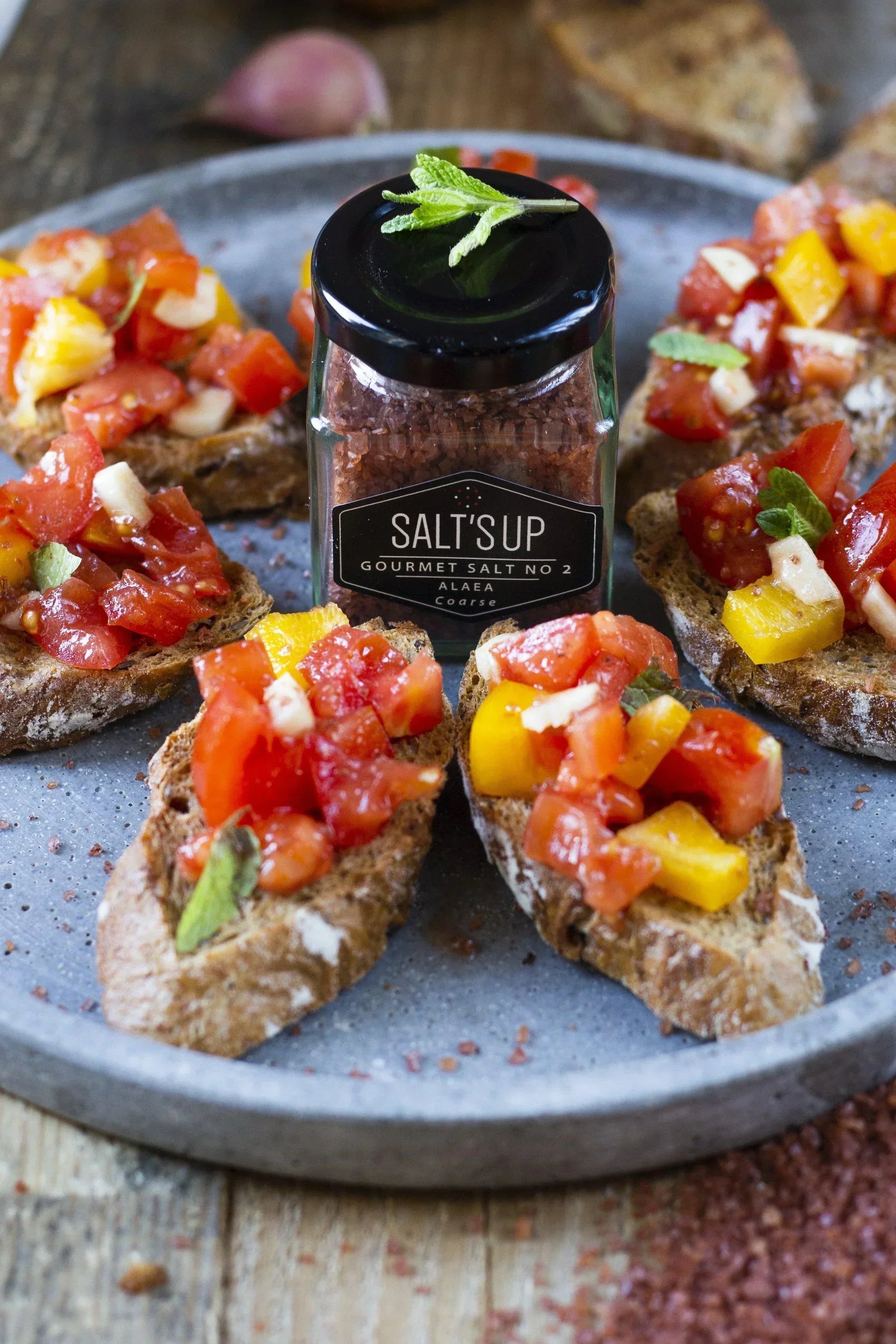 Gourmet Alaea coarse salt jar on plate with tomato bruschetta, artisan food at Spice n Slice Market