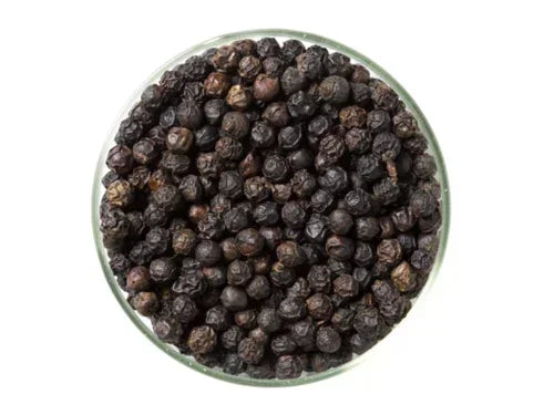 Glass bowl filled with whole black peppercorns on a white background