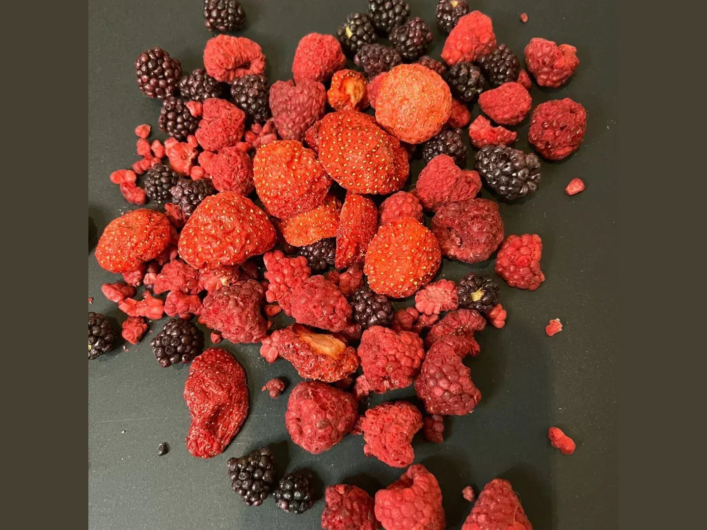 Freeze-dried organic berry mix with strawberries, raspberries, blackberries on dark background
