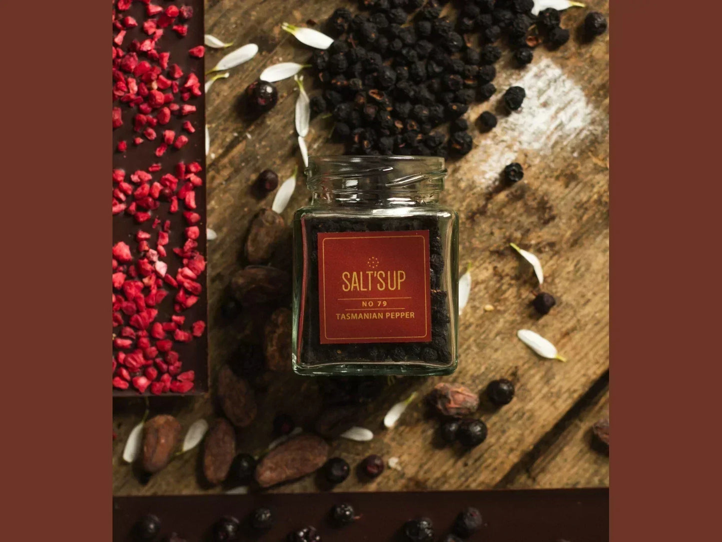 Tasmanian pepper in a glass jar on rustic wood, with chocolate bar and dried berries