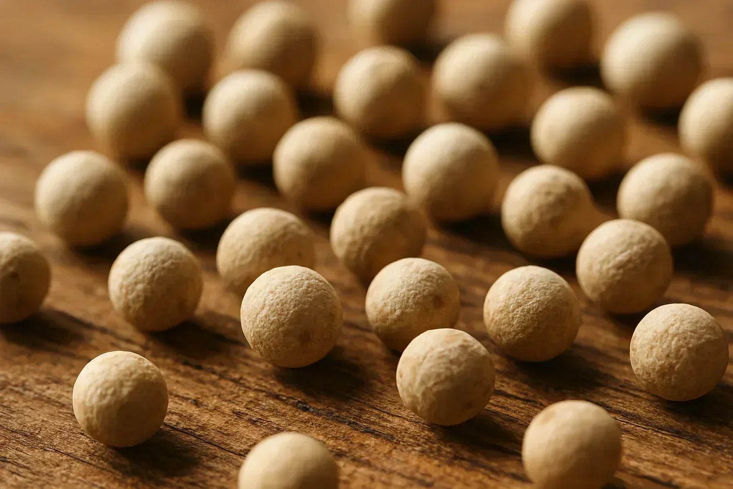 Macro close-up of whole white peppercorns on a wooden surface