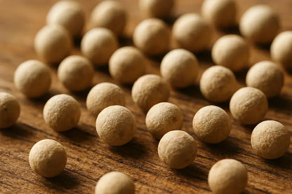 Macro close-up of whole white peppercorns on a wooden surface