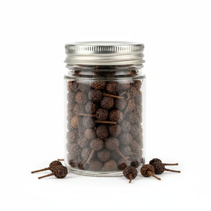 Cubeb peppercorns with visible tails in a clear glass jar on white background