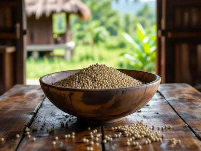 Wooden bowl of white peppercorns on rustic table with greenery outside