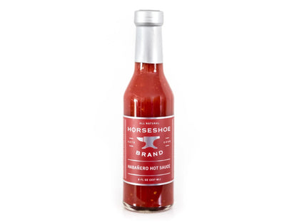 Glass bottle of habanero hot sauce with red label and silver cap on white background
