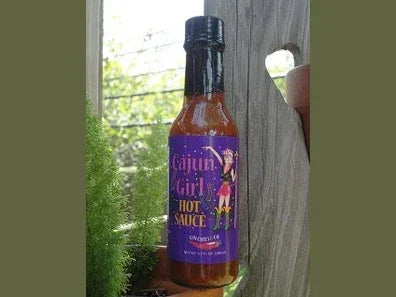 Cajun Girl hot sauce bottle outdoors, artisan spicy condiment with purple label