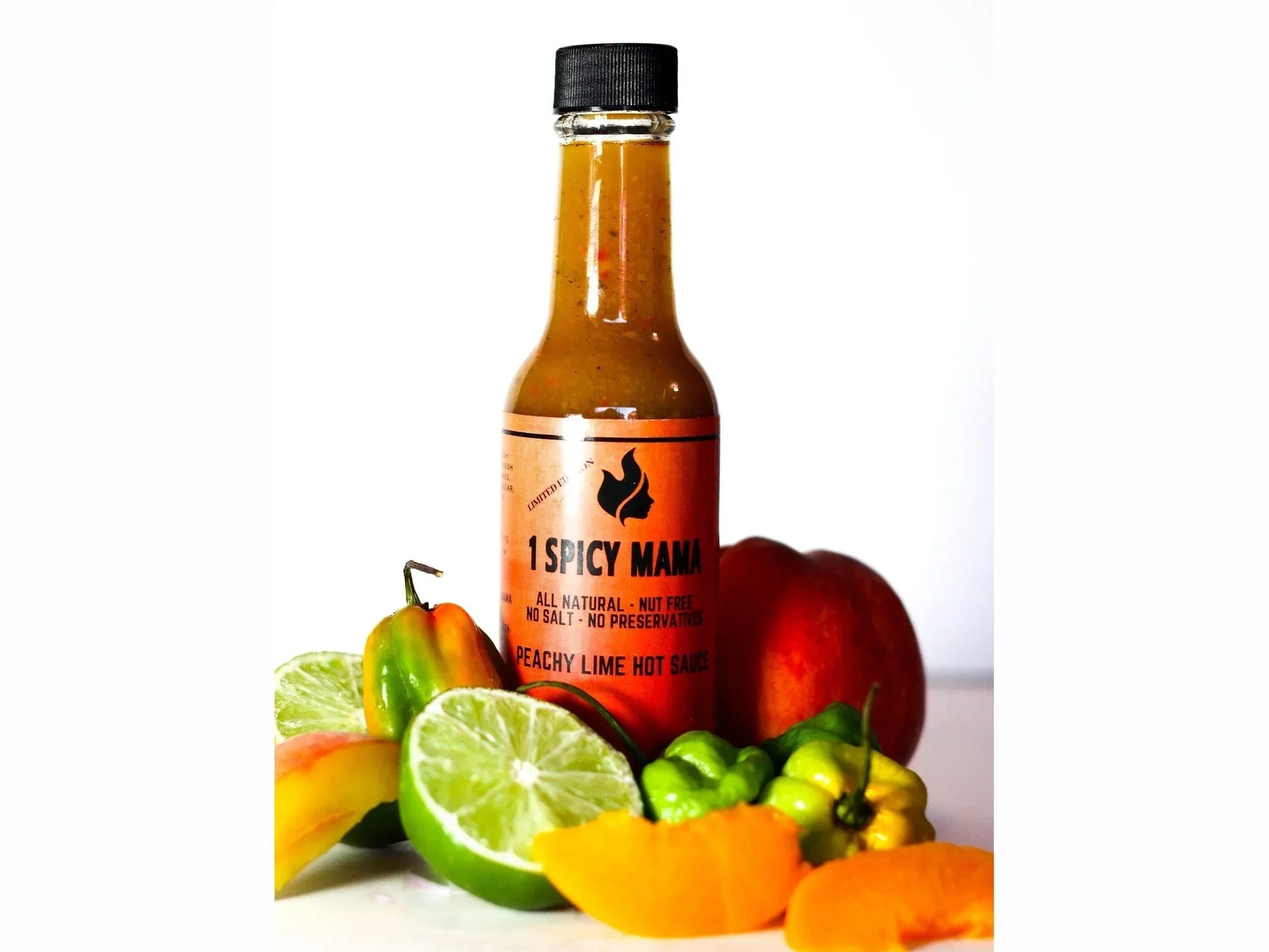 Peachy lime hot sauce bottle with fresh lime, peach, and peppers on white background