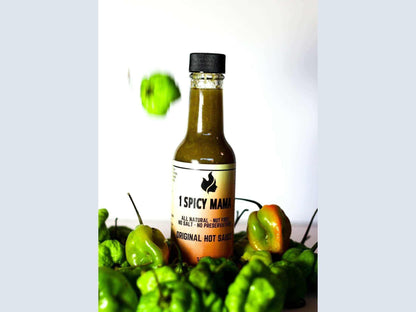 Original hot sauce bottle surrounded by fresh green peppers on white background