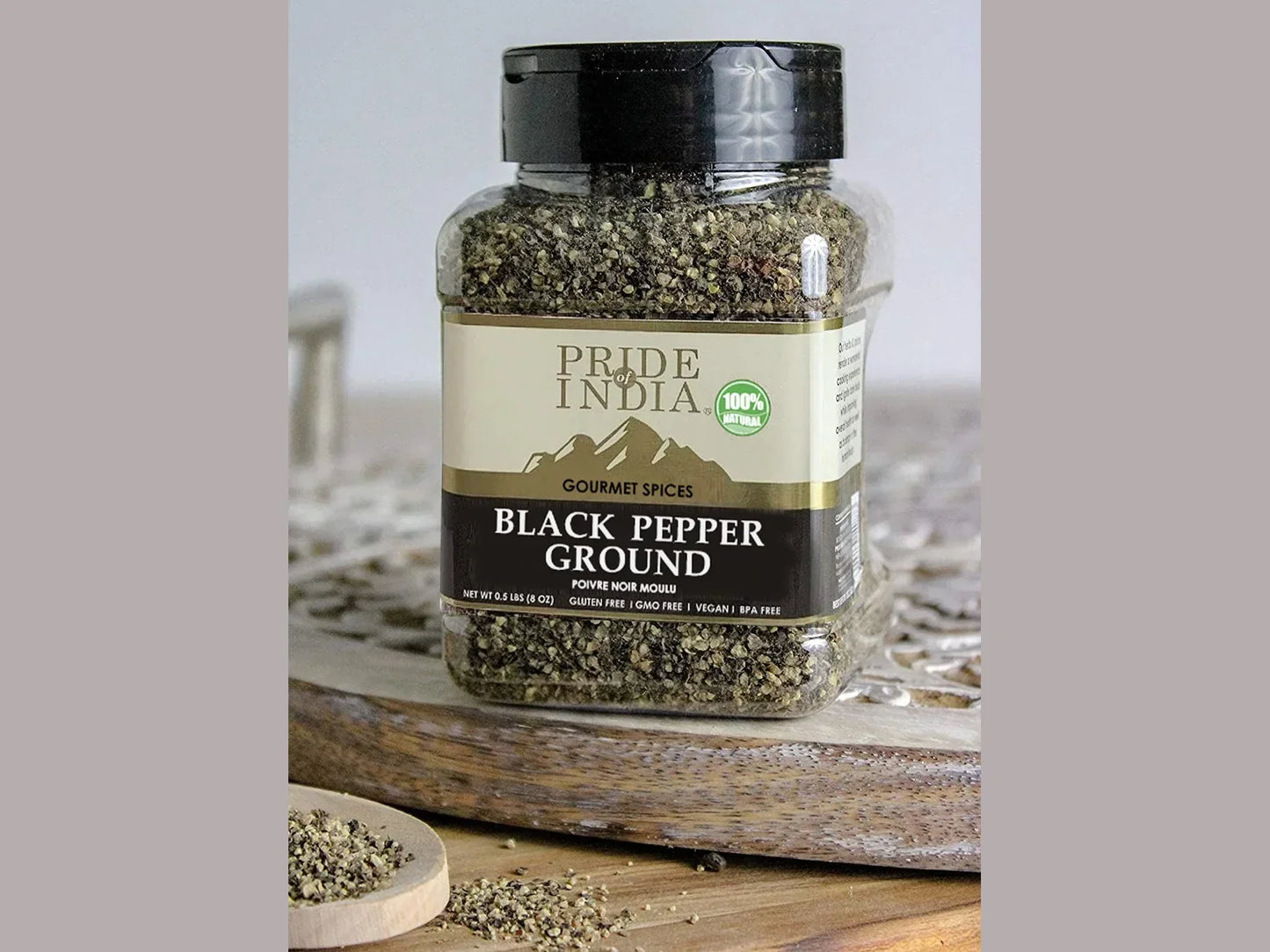 Jar of ground black pepper on a wooden board, labeled Pride of India gourmet spices