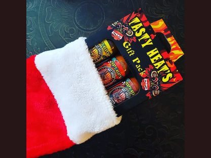 Tasty Heats hot sauce gift pack in a Christmas stocking on a dark patterned surface.