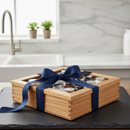 Wooden spice gift box with navy ribbon, filled with glass jars, displayed in a kitchen