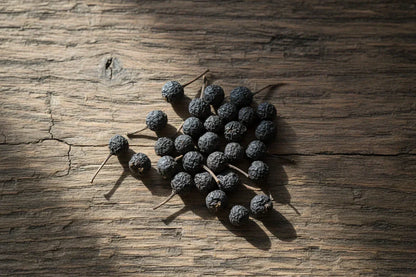 Whole dried PGI Kampot peppercorns on rustic wood, Spice n Slice Market gourmet spice