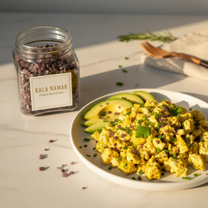 Kala Namak coarse black salt jar beside scrambled tofu with turmeric and avocado