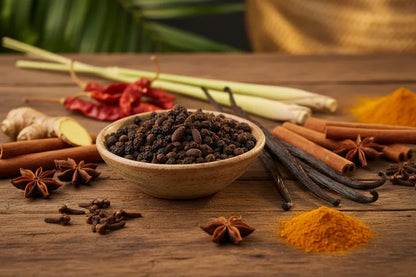 Assorted spices including black pepper, cinnamon sticks, star anise, and turmeric on rustic wood