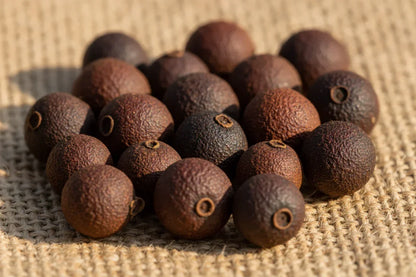 Whole dried black peppercorns on burlap, gourmet spice close-up