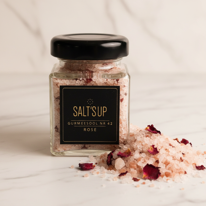 Rose gourmet salt blush-pink crystals macro close-up with dried rose petals on white marble