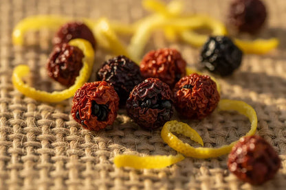 Whole dried Kampot peppercorns and lemon peel on woven mat close-up