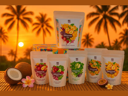 Assorted smoothie mix pouches with tropical fruit and coconut on bamboo mat at sunset