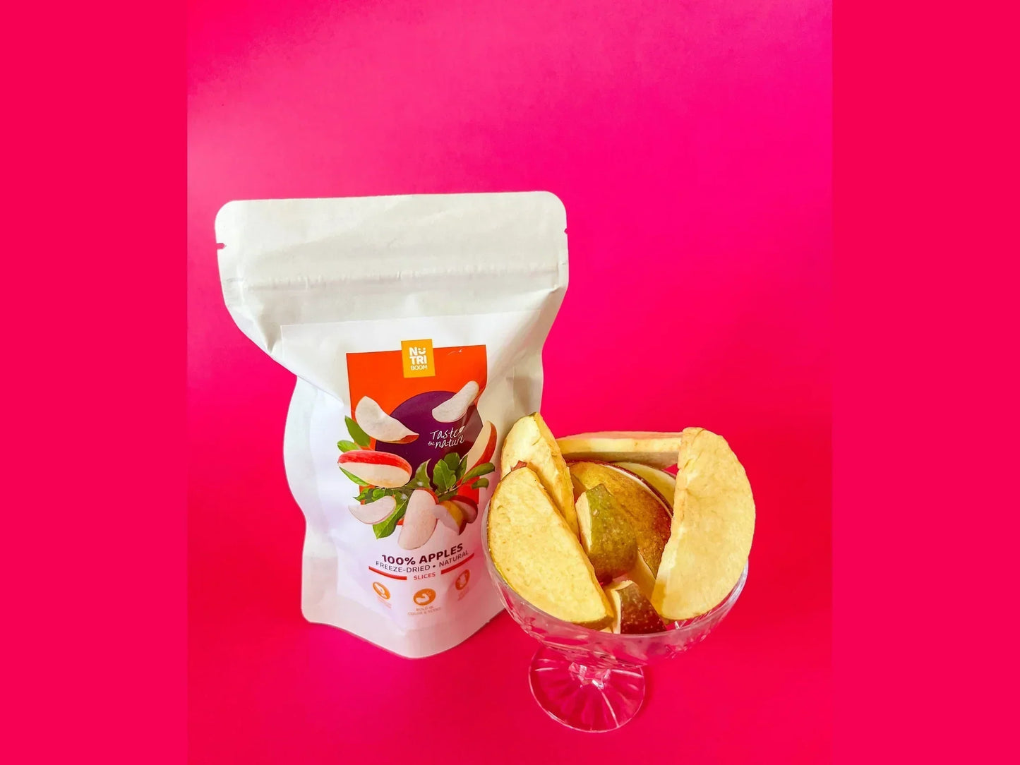 Freeze-dried apple slices in a glass bowl and resealable pack on pink background