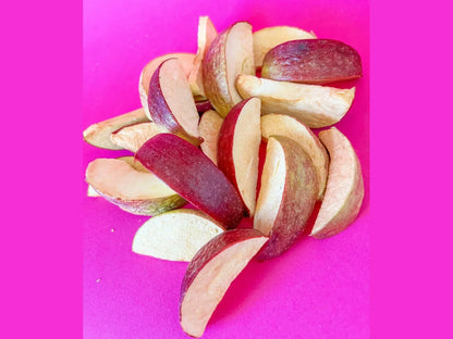 Organic dried apple slices with red peel on a bright pink background