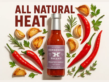 Roasted garlic hot sauce bottle with fresh chili peppers, garlic cloves, and herbs arranged around it.