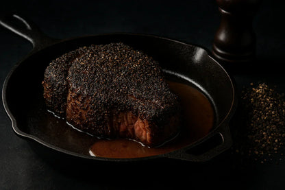 Pepper-crusted steak in cast iron pan with black pepper and pan sauce