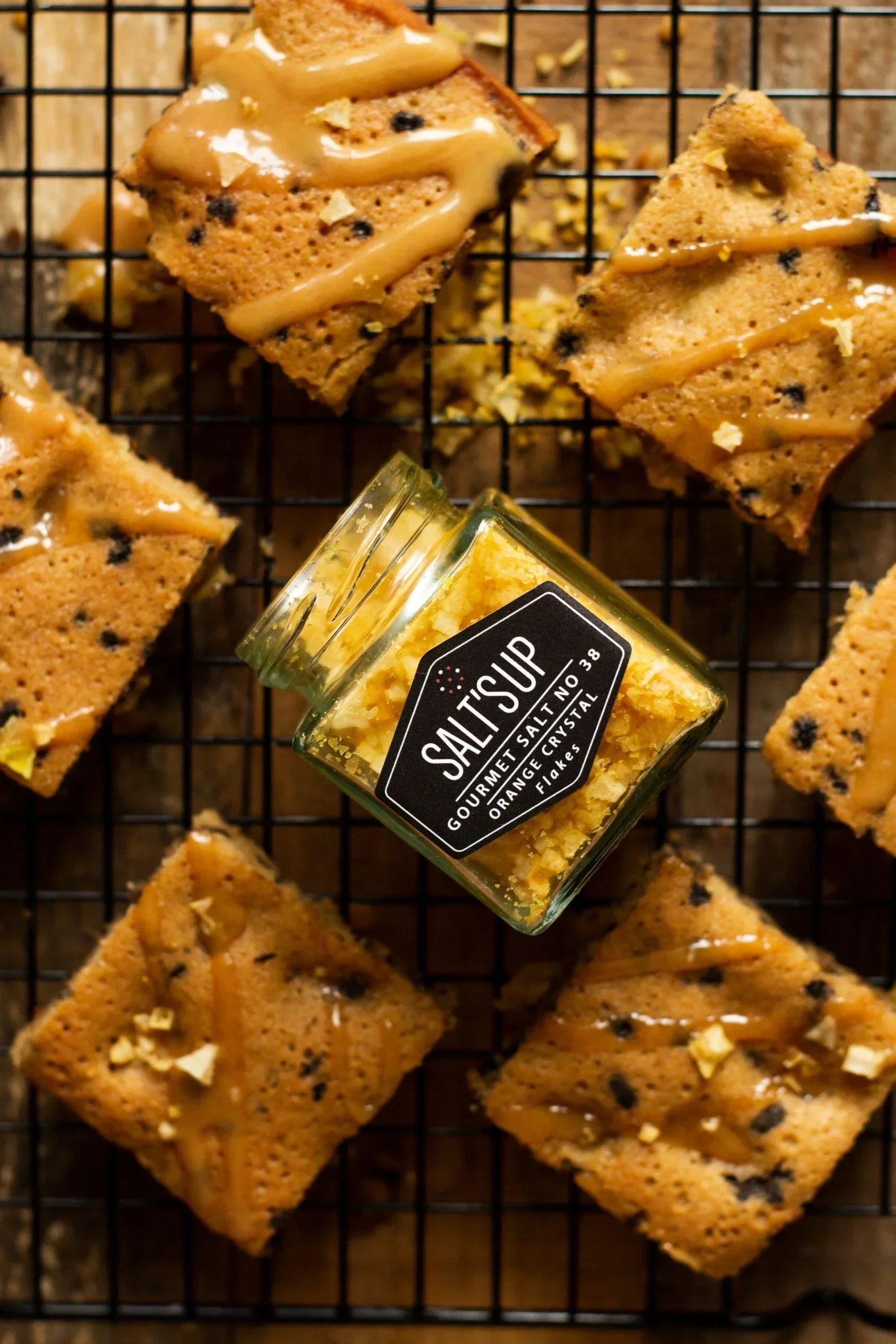 Gourmet orange crystal salt jar on cooling rack with caramel-drizzled blondies, Spice n Slice Market