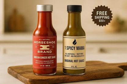 Two bottles of hot sauce on wooden board, Horseshoe Brand Korean Ginger and 1 Spicy Mama Original, free shipping offer.